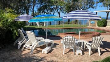 Relax by the pool surrounded by lush greenery and comfortable lounge chairs.