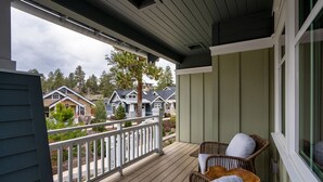 A covered porch with wicker furniture and a view of neighboring houses. - Art Collector's Sophisticated NW Crossing Home (Bend)