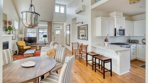 A spacious living area with a dining table, sofas, and a kitchen with white cabinets and a central island. - Art Collector's Sophisticated NW Crossing Home (Bend)