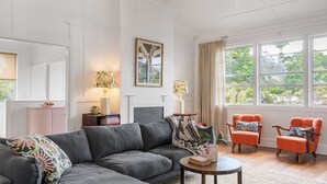 A living room with a grey sofa, two orange armchairs, a small round table, and a fireplace.