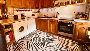 Cocina con armarios de madera, microondas, estufa y lavavajillas.