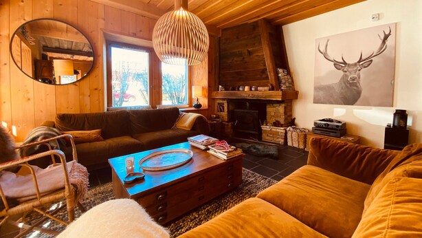 Una sala de estar acogedora con chimenea, techo de madera y un espejo grande.