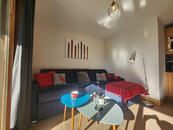 Un salon avec un canapé, une table basse, un lampadaire et un tableau accroché au mur.