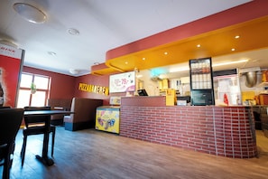 A pizza restaurant interior with seating, a counter, and a menu display. - Topcamp Mosjøen - Helgeland (Vefsn)
