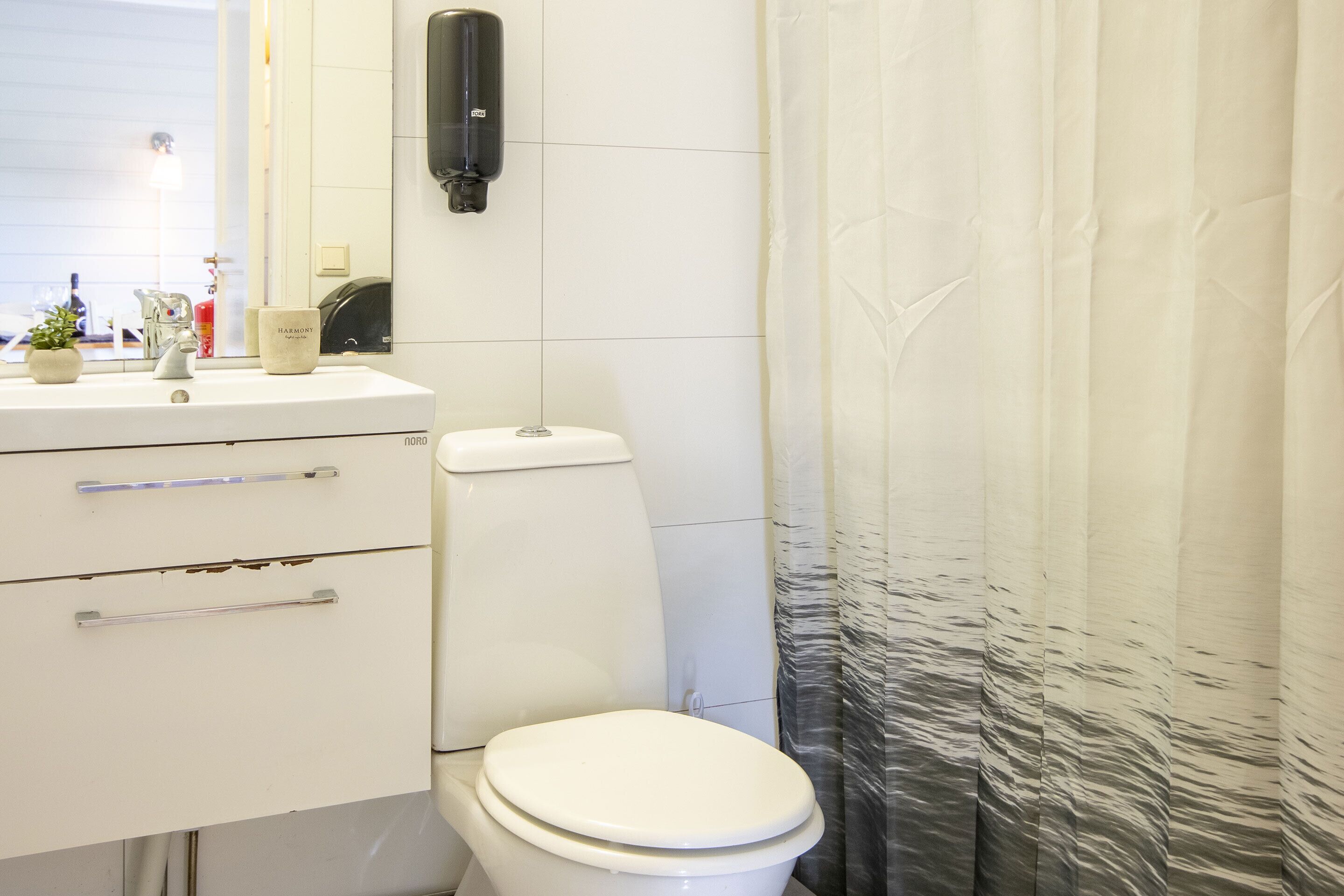 Un bagno con lavandino bianco, specchio, servizi igienici e tenda della doccia.