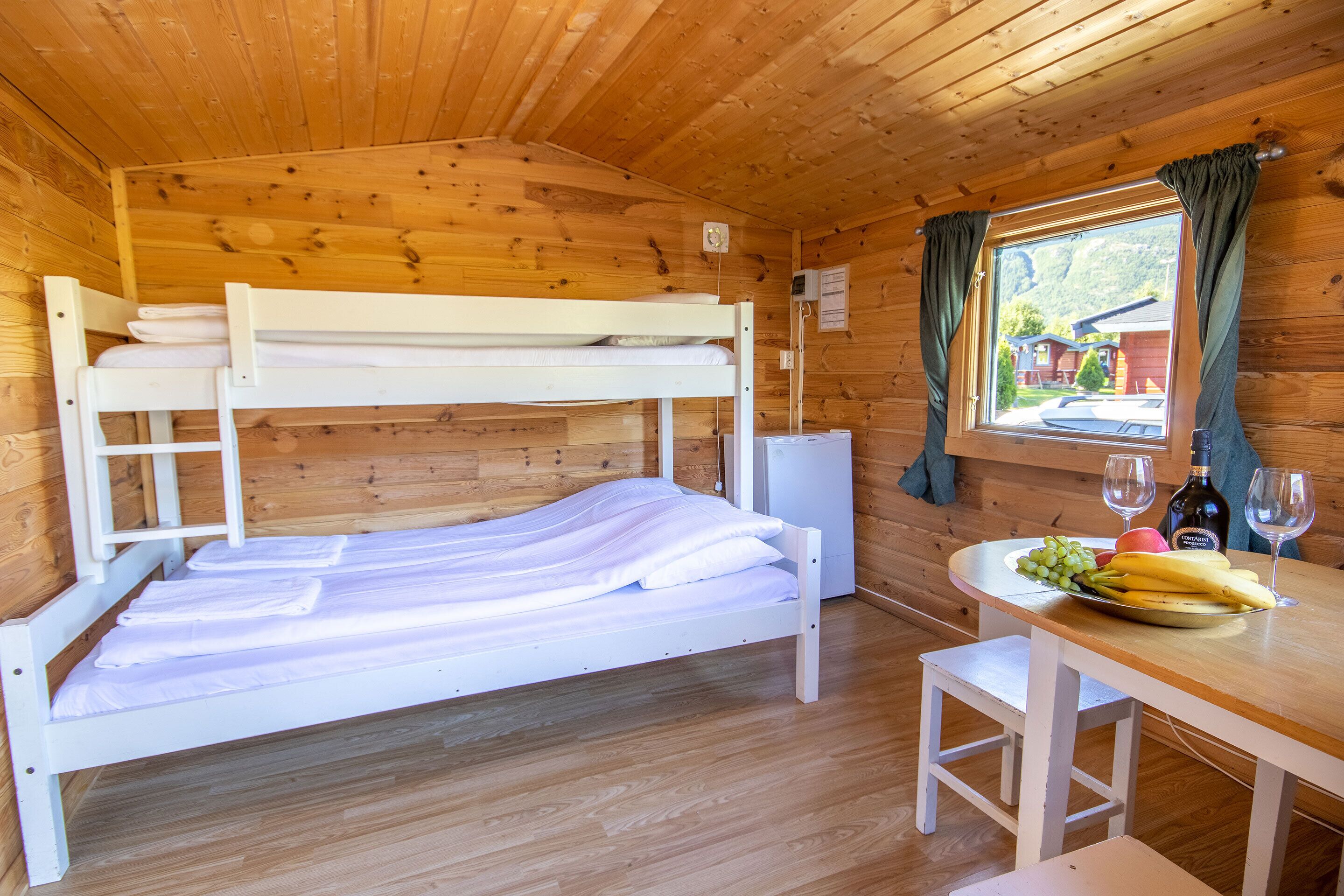 A bunk bed with a table and a window with curtains.