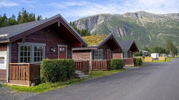 A row of wooden cabins with a mountain backdrop. - Topcamp Mosjøen - Helgeland (Vefsn)