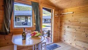 A wooden cabin interior with a table set for two, a bottle of wine, and a bowl of fruit. - Topcamp Mosjøen - Helgeland (Vefsn)