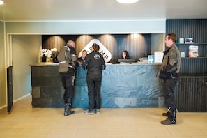 A reception desk with a sign, a counter, and a wall with vertical lines. - Topcamp Mosjøen - Helgeland (Vefsn)