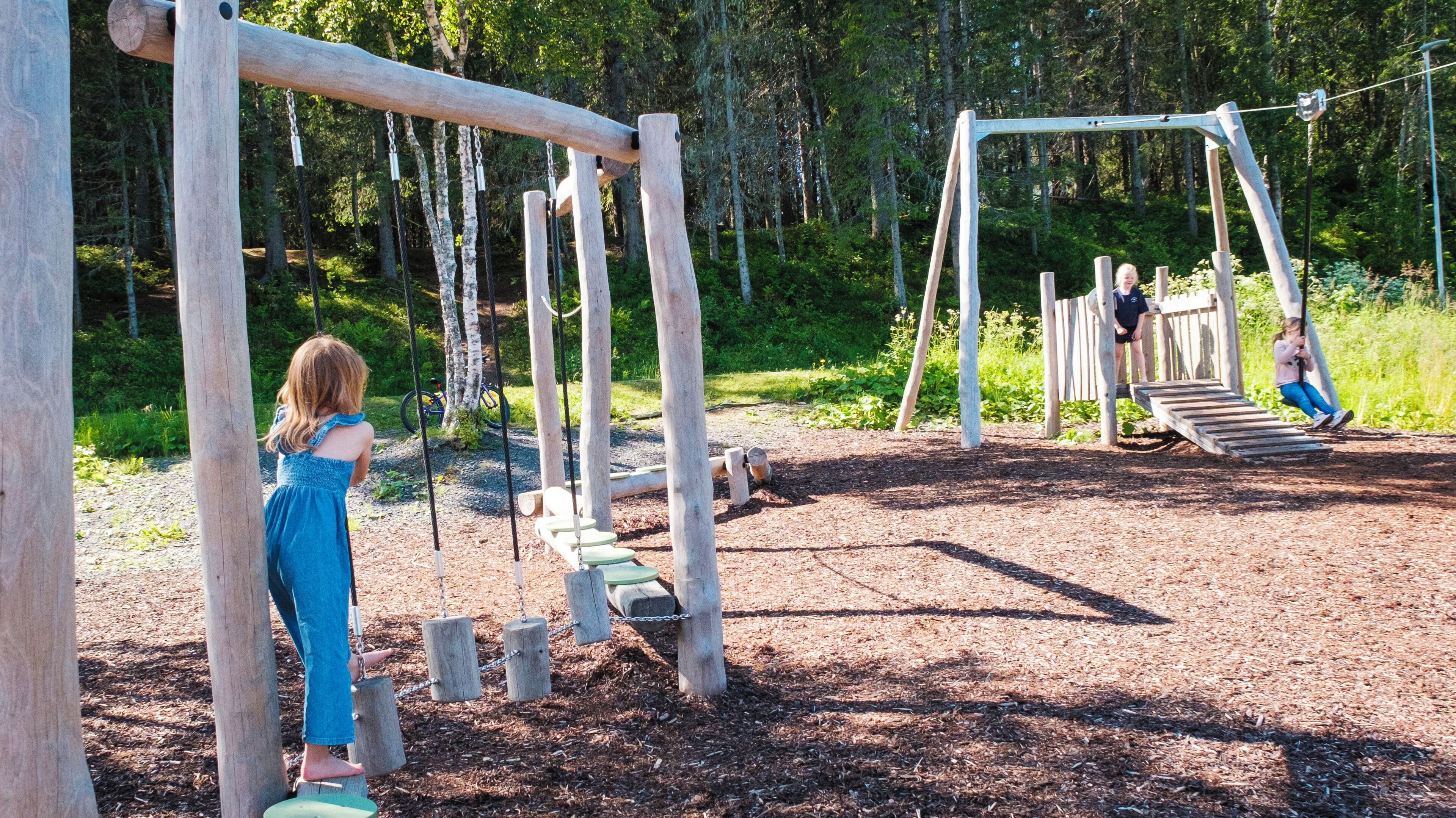 A playground with wooden structures and a dirt ground.