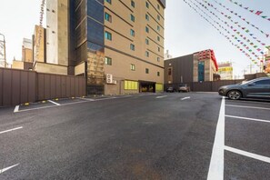 A parking lot with a building entrance, marked parking spaces, and a visible tunnel entrance. - HOTELIUM (Cheonan)