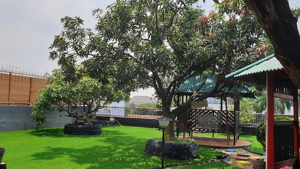 A well-maintained garden with a variety of trees, a gazebo, and a fenced area. - Wir Hotel (Jakarta)
