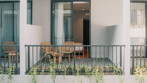 A balcony with wicker furniture and a view of the interior. - Bestah Coliving (Denpasar)