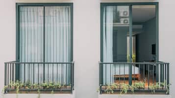 Dos balcones con barandillas de metal y macetas con plantas.