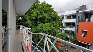 A balcony with a white railing overlooking a residential area with trees and buildings. - City Style Residence (Jakarta)