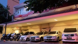 A multi-story building with a parking area. There are several cars and motorcycles parked in front. - City Style Residence (Jakarta)