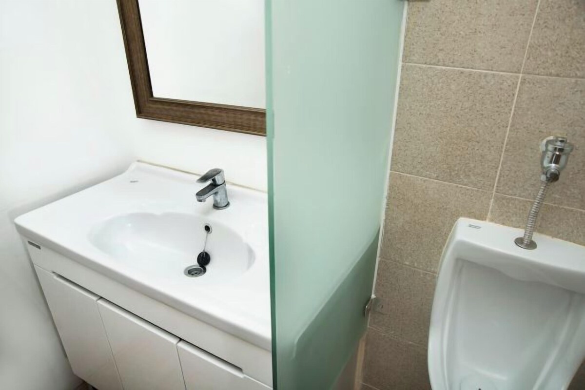 A bathroom with a white sink, a mirror, and a urinal.