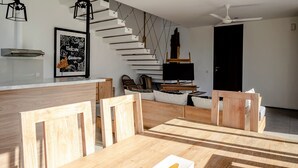 Una cocina moderna con una mesa y sillas de madera, una escalera y un cartel de bienvenida enmarcado.