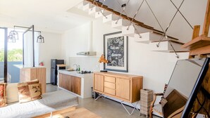 Una sala moderna con un sofá, un mueble de madera y una zona de comedor con una cocina al fondo.