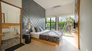 A modern bedroom with a bed, bedside table, and a view of greenery outside. - Maitreya Villa (Jimbaran)