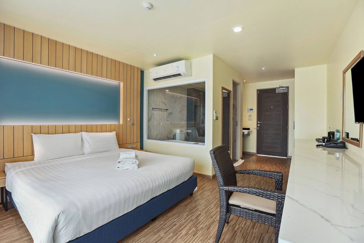 Habitación de hotel con una cama grande, ducha, zona de estar y televisor.