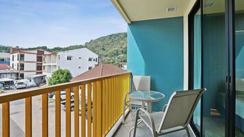 Een balkon met een gele reling, een glazen tafel en twee stoelen.