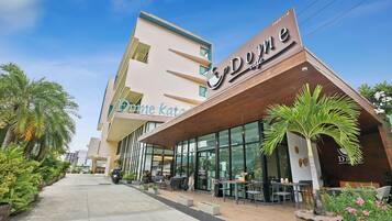 A modern building with a cafe named "Dome" on the ground floor, featuring outdoor seating and palm trees.