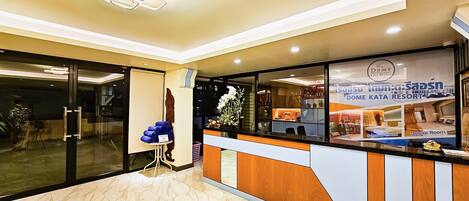 A hotel reception area with a marble floor, a reception desk, and a glass door leading to the lobby.