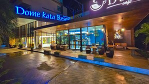 The exterior of Dome Kata Resort with a well-lit entrance, outdoor seating area, and large windows. - Dome Kata Resort (Karon)