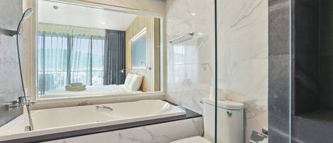 A modern bathroom with a large bathtub, a toilet, and a glass-enclosed shower area.