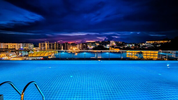 A swimming pool with a cityscape view at night. - Dome Kata Resort (Karon)