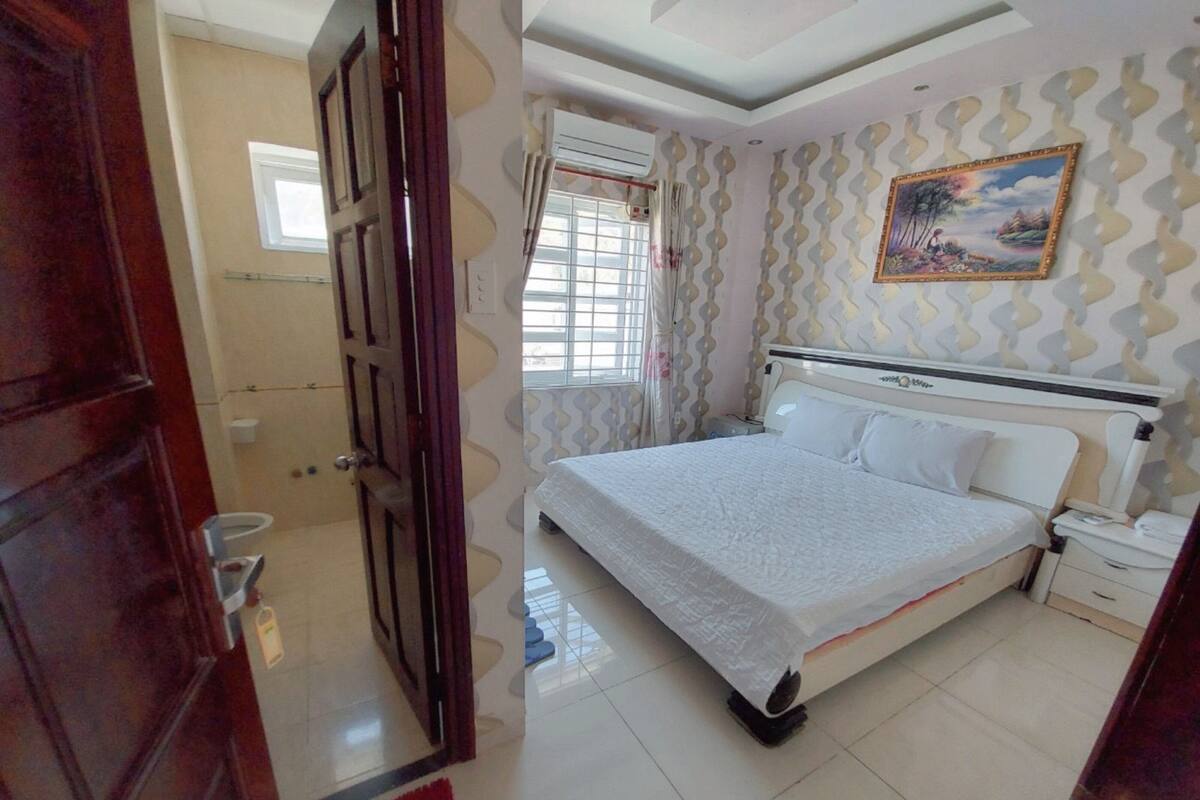 A bedroom with a bed, a nightstand, a window with curtains, and a door.