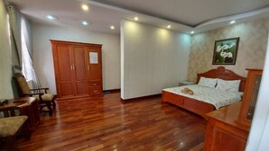 Ein Schlafzimmer mit Holzboden, einem Bett mit Kopfteil, einem Kleiderschrank und einem Schreibtisch mit Stuhl.