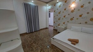 Ein modernes Hotelzimmer mit einem großen Bett, einem weißen Kleiderschrank, einem Badezimmer mit Dusche und einer Wand mit Muster.