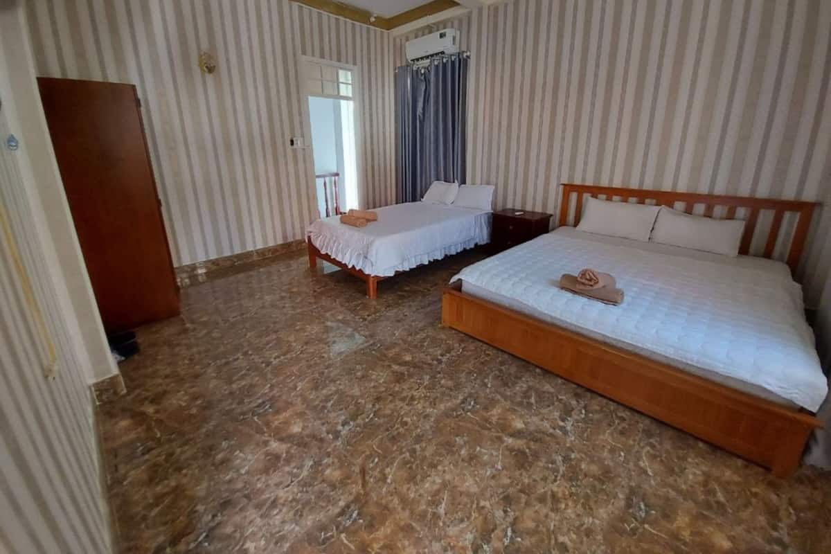 A hotel room with two beds, a marble floor, striped wallpaper, and a ceiling fan.