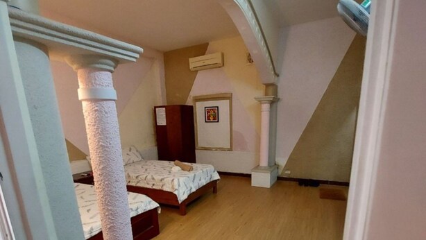 Ein Schlafzimmer mit Holzboden, einem Bett, einem kleinen Tisch und einem Bild an der Wand.