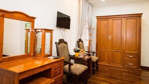Ein Zimmer mit einem Holzkasten, einem an der Wand montierten Fernseher, einem großen Kleiderschrank und zwei Stühlen.