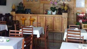 L’intérieur d’un hôtel, avec des lambris en bois, un comptoir d’accueil et plusieurs tables et chaises.