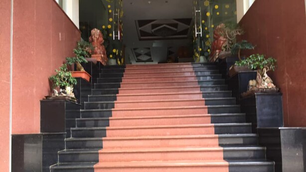 Un escalier menant à l’entrée d’un bâtiment, avec des plantes en pot de chaque côté.