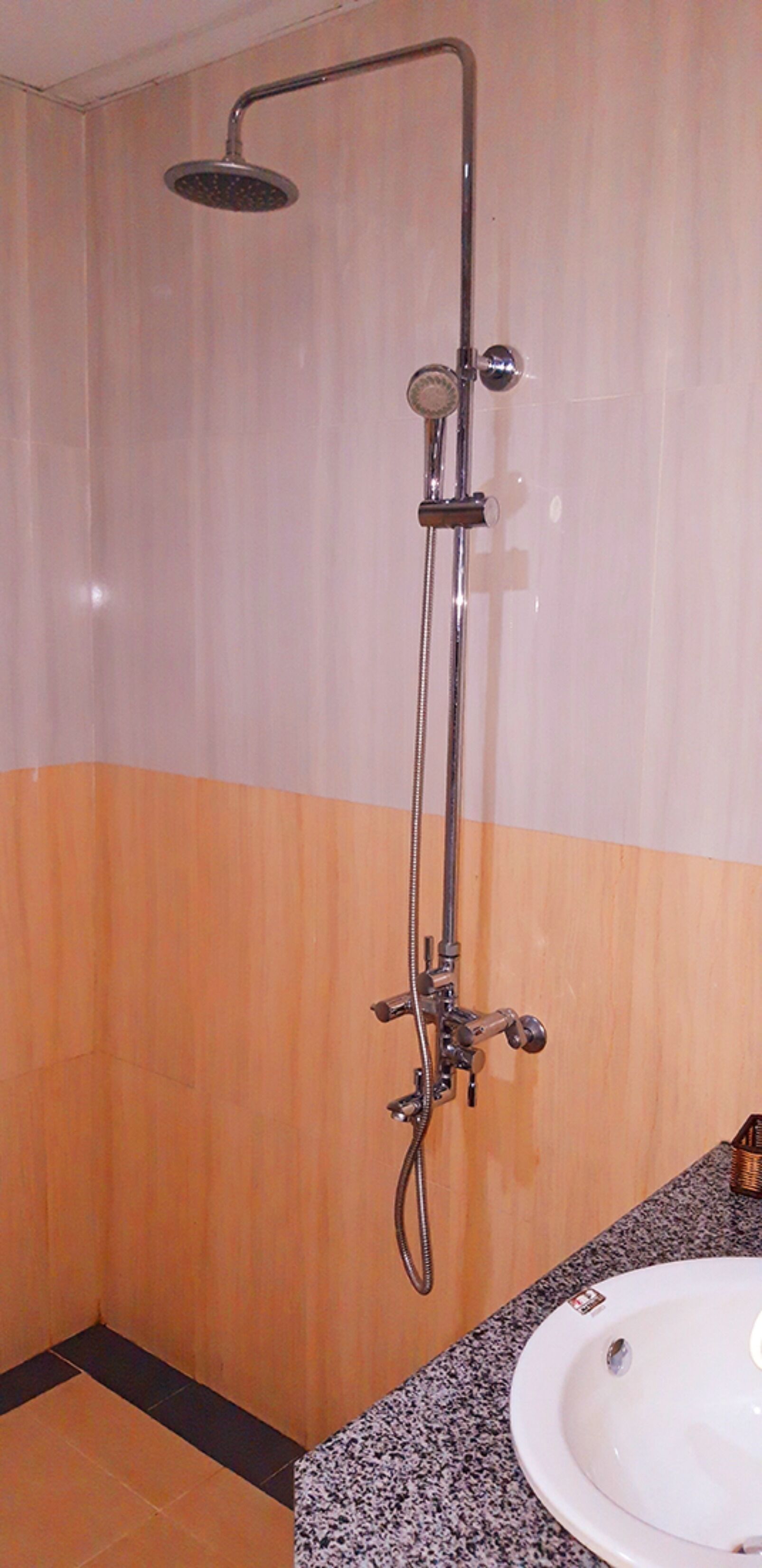 A shower with a handheld showerhead and a wall-mounted faucet.