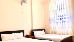 Una habitación de hotel con dos camas individuales, una mesita de noche con teléfono y un ventilador de techo.