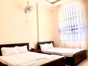 Una habitación de hotel con dos camas individuales, una mesita de noche con teléfono y un ventilador de techo.