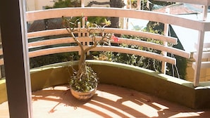 A balcony with a potted plant, a railing, and a view of neighboring buildings. - Hoa Hong Do Guesthouse (Xuan Huong - Da Lat)