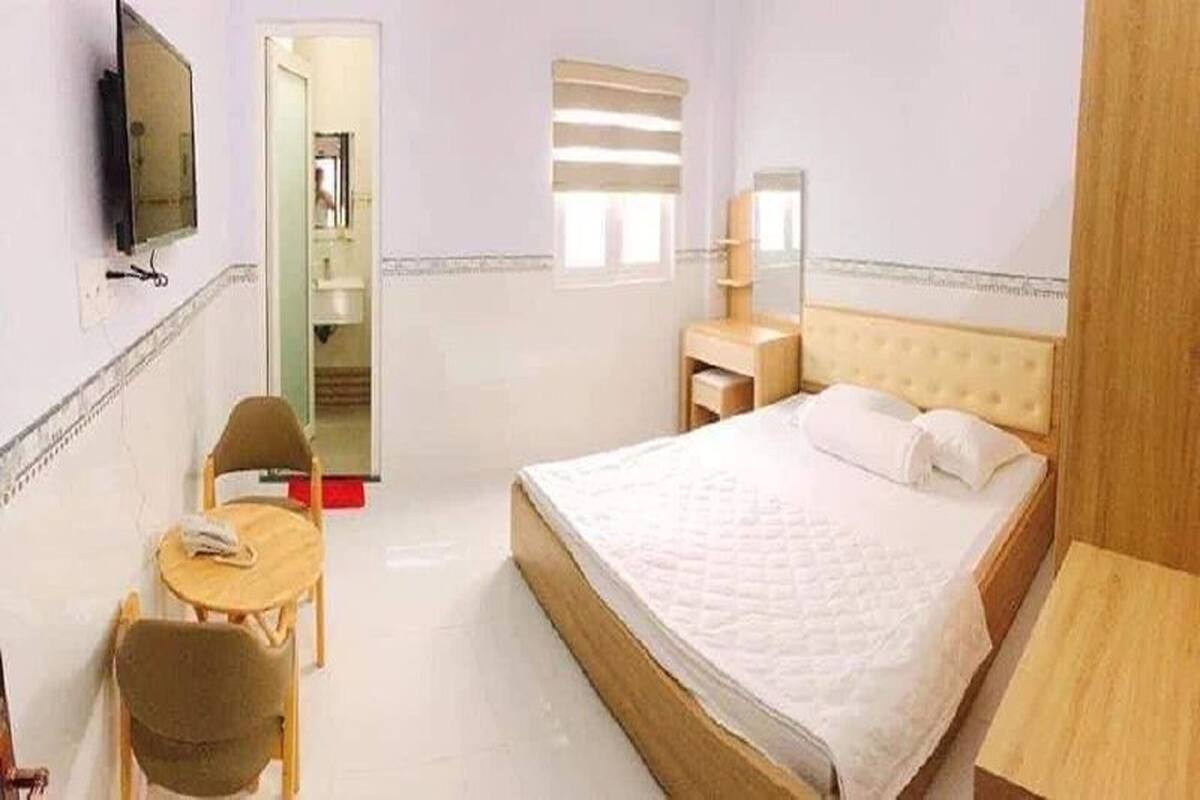Una habitación de hotel con cama, escritorio, silla, televisor y espejo.