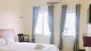 A hotel room with a bed, a chair, an air conditioning unit, and a window with curtains. - Kings 2 Hotel (Thong Nhat)