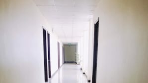 A long, narrow hallway with a shiny tiled floor and white walls. - Kings 2 Hotel (Thong Nhat)