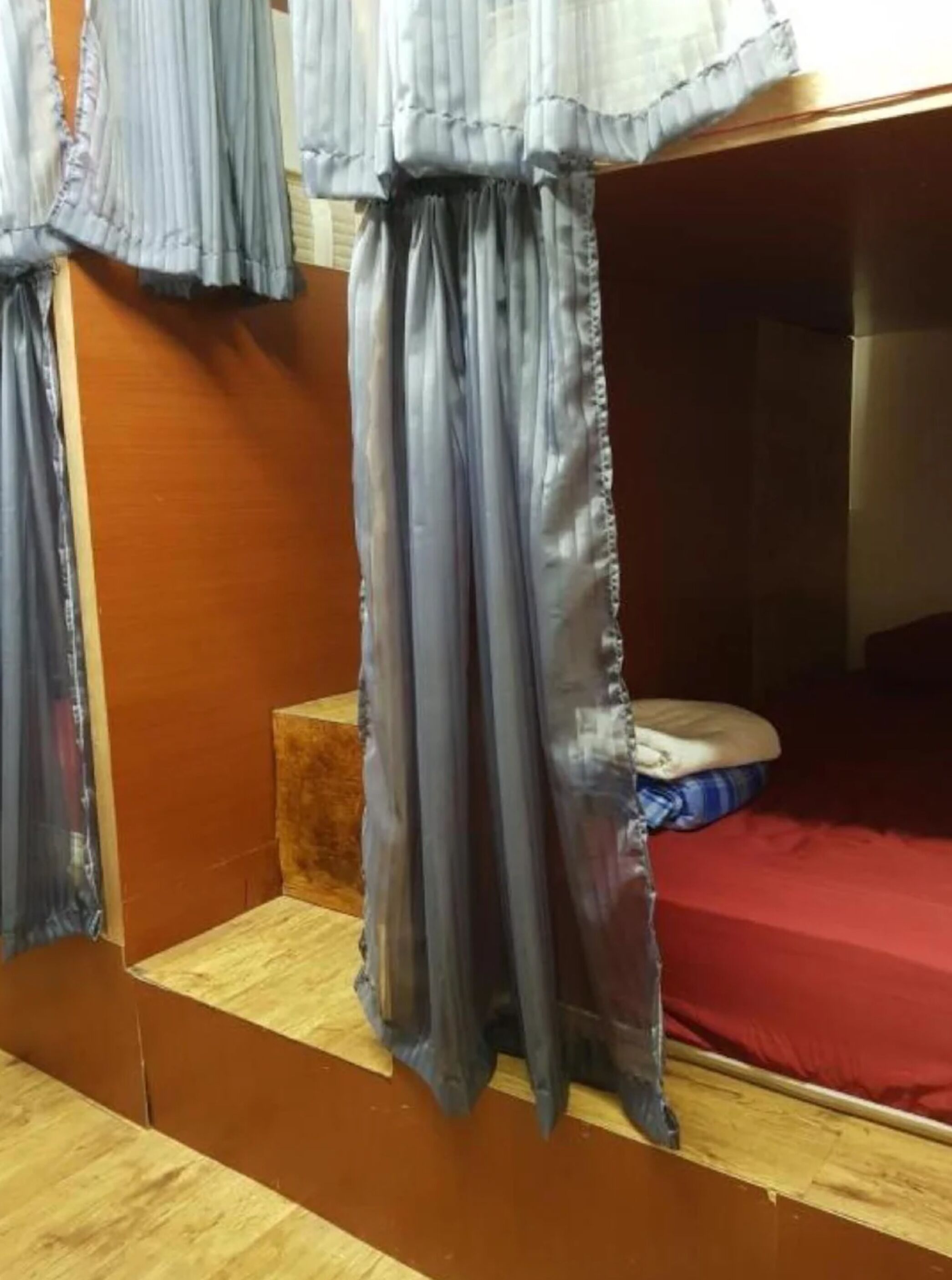 A bunk bed with a red mattress and a wooden platform.