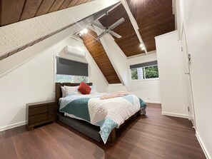 Cozy retreat with a sloped ceiling, featuring a comfortable bed and a ceiling fan.