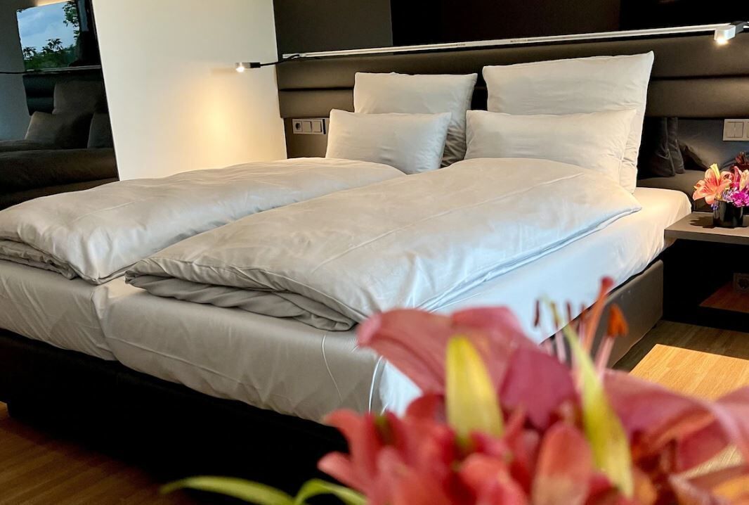 A modern hotel room with a large bed, a bedside table, and a nightstand.