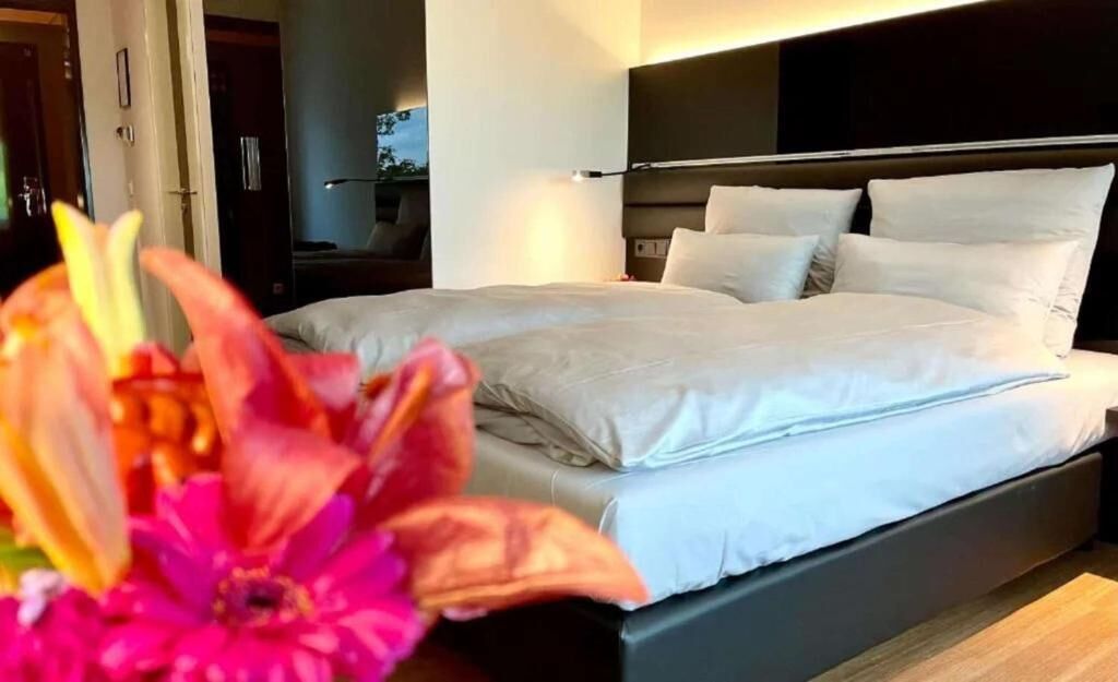 A modern bedroom with a large bed, a headboard, and a nightstand.